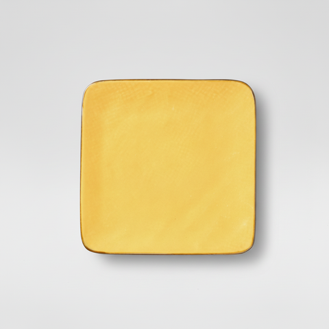Piatto giallo quadrato su sfondo grigio con ombra