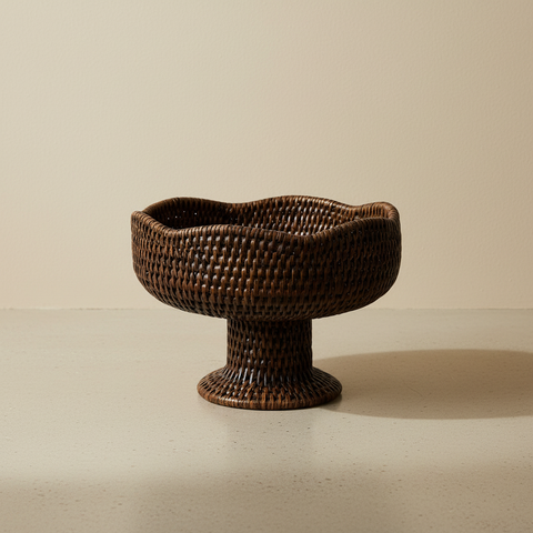 Alzata porta frutta in rattan con base rialzata e bordo ondulato su sfondo beige