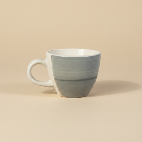 Tazza in ceramica grigio-blu su sfondo beige con ombra