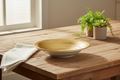 Piatto bianco oro vuoto ambientato su tavola rustica