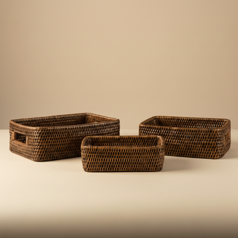 Set di 3 cestini rettangolari in rattan con maniglie su sfondo beige neutro