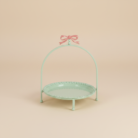 Alzatina verde menta con fiocco rosa su sfondo beige con ombra