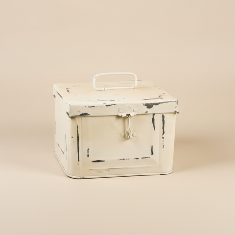 Scatola metallo crema su sfondo beige con ombra