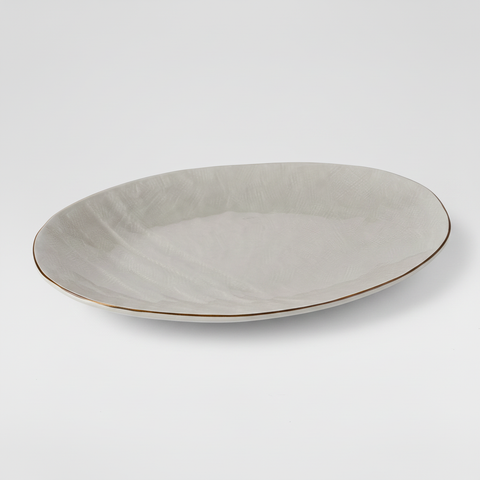 Vassoio ovale bianco crema con bordo dorato su sfondo grigio