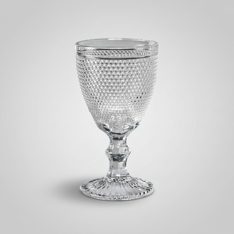 Calice in cristallo trasparente hobnail su sfondo grigio con ombra