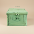 Scatola metallo verde chiaro su sfondo beige con ombra