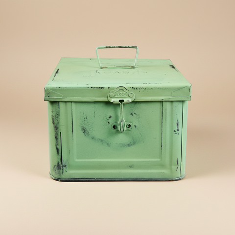 Scatola metallo verde chiaro su sfondo beige con ombra