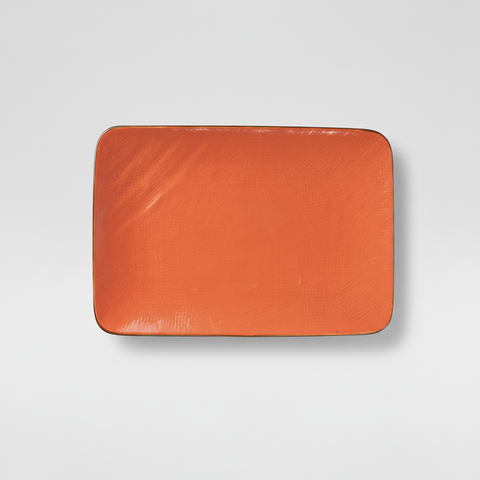 Piatto arancione rettangolare su sfondo grigio chiaro con ombra