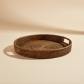 Vassoio tondo in rattan con maniglie su sfondo beige neutro
