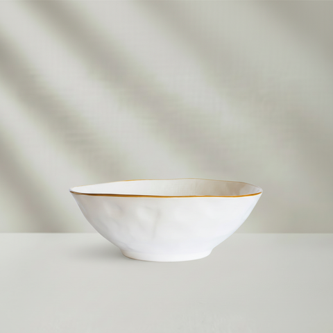 Insalatiera bianca con bordo dorato su sfondo grigio