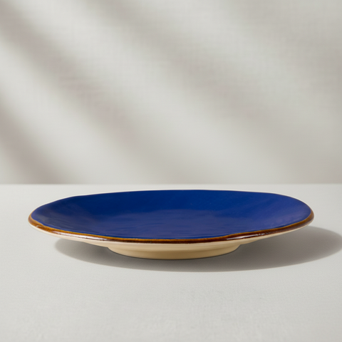 Piatto ceramica blu con bordo oro su sfondo grigio