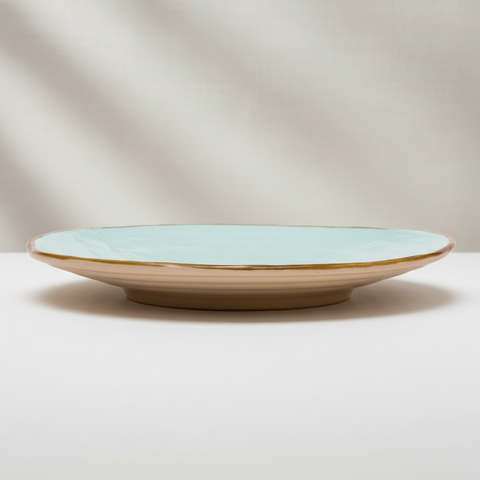 Piatto ceramica turchese con bordo oro su sfondo grigio chiaro quadrato