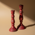 Portacandele in legno rosso su sfondo neutro con ombre