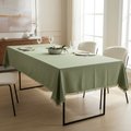 Tovaglia verde salvia con bordo sfrangiato su tavolo rettangolare